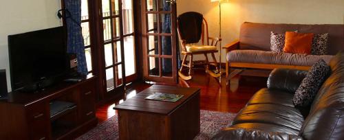 a living room with a couch and a tv at Clover Cottage Country Retreat in Manjimup