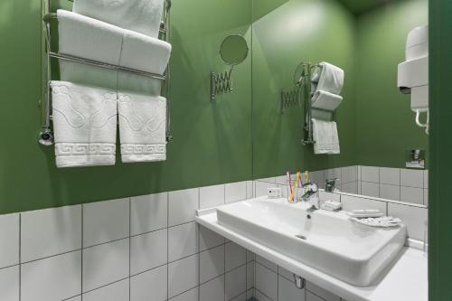 a bathroom with a sink and a green wall at City Hotel Bortoli by Ribas in Odesa