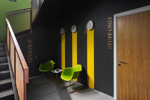 a hallway with green chairs and clocks on the wall at City Hotel Bortoli by Ribas in Odesa