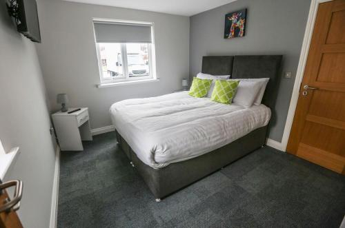a bedroom with a bed with green and white pillows at Hotel 52 Stanley in Stanley