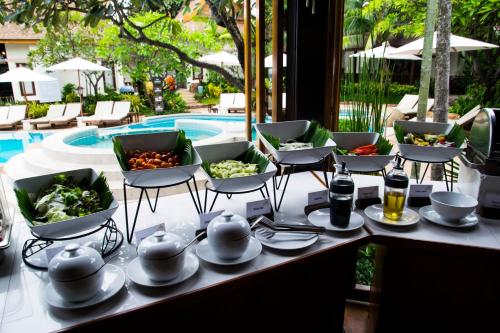 a table with plates and bowls of food next to a pool at Thai House Beach Resort in Lamai