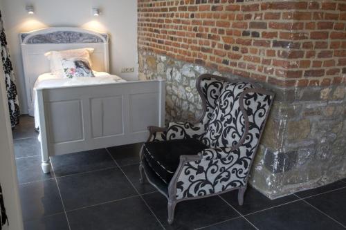 a living room with a chair and a brick wall at Meschermolen in Mesch