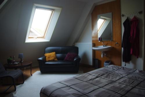 a bedroom with a bed and a chair and a sink at B&B Noflik Haule in Haule