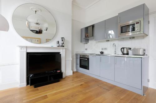 ロンドンにあるALTIDO Cosy 1-bed flat in Angel, close to tubeの白いキャビネットと大きな鏡付きのキッチン