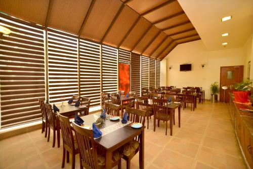 a restaurant with wooden tables and chairs in a room at Pink Pearl Hotel By Chokhi Dhani in Jaipur