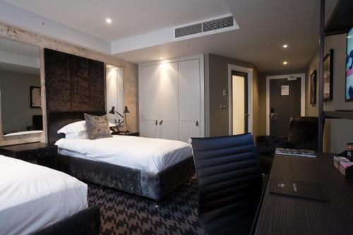 a hotel room with two beds and a desk at Malmaison Birmingham in Birmingham