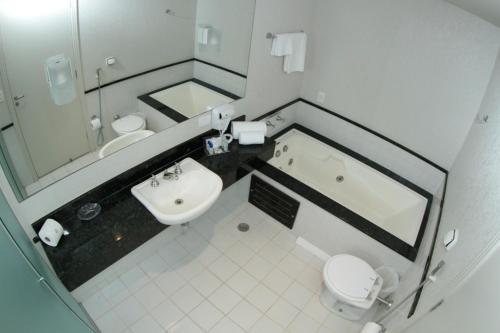 a bathroom with a sink and a toilet and a tub at Hotel Metrópole Maringá in Maringá