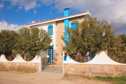 a building with blue windows and a fence at La Casa Sulla Spiaggia in Flumini di Quartu