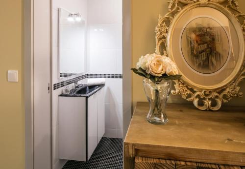 a bathroom with a mirror and a vase with flowers on a table at Camarinha Oporto Apartments in Porto