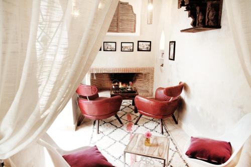 a living room with red chairs and a fireplace at Riad 11 Zitoune in Marrakesh