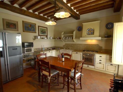 a kitchen with a wooden table and a refrigerator at Villa La Pergola in Cortona