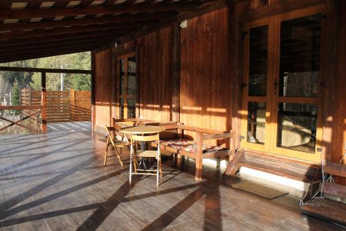 a porch of a wooden cabin with a table and chairs at Чан-садиба Гуцульська пісня in Mykulychyn