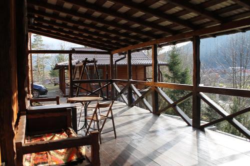 eine abgeschirmte Veranda mit einem Tisch und Stühlen darauf in der Unterkunft Чан-садиба Гуцульська пісня in Mykulytschyn