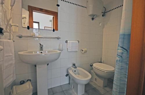 a white bathroom with a sink and a toilet at Locanda Menabuoi in Donoratico