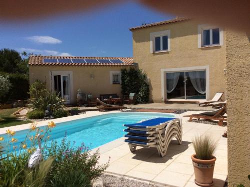 a villa with a swimming pool in front of a house at Le Claouraous calme in Canet