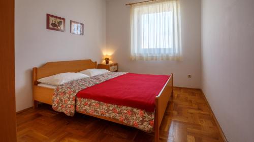 a bedroom with a bed with a red blanket and a window at Apartment Josephine 2 in Malinska