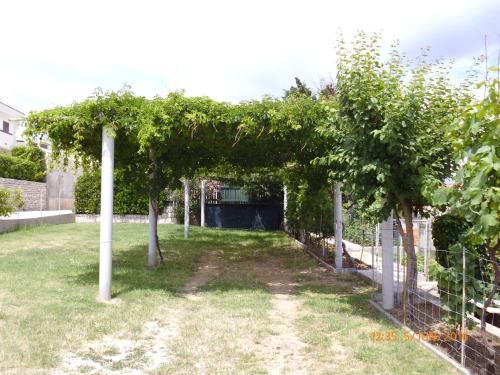 a pergola with trees in a yard at Apartments Lidija in Pag