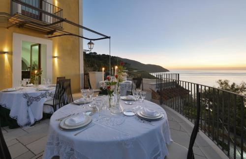a table with white table cloths on a balcony with the ocean at San Francesco Resort in Agropoli