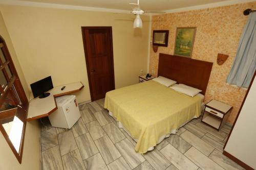 a bedroom with a bed and a desk and a computer at Pousada Vitória in Ilhéus
