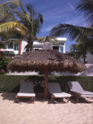 two chairs and a straw umbrella on the beach at The Cliff Residence in Mui Ne