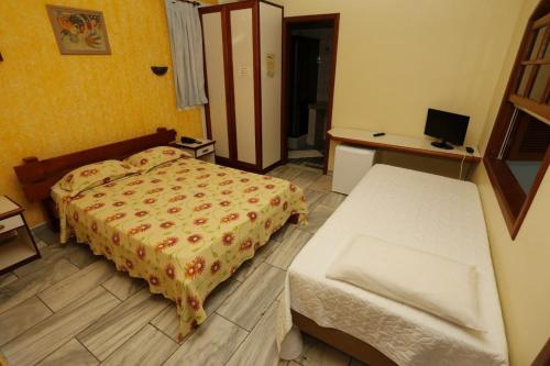 a hotel room with a bed and a desk and a bed and a bedskirts at Pousada Vitória in Ilhéus