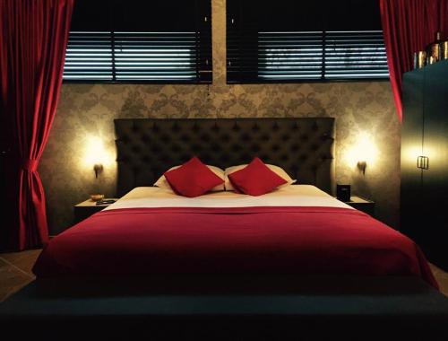 a bedroom with a large bed with red pillows at VillaluX in Kortessem
