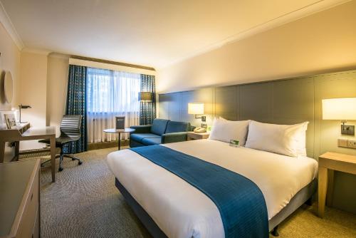 una camera d'albergo con un grande letto e una scrivania di Holiday Inn Cambridge, an IHG Hotel a Cambridge
