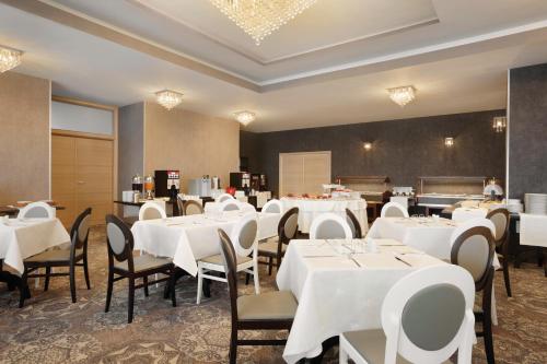 a dining room with white tables and chairs at Ramada by Wyndham Constanta in Constanţa