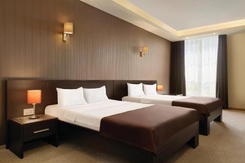 a hotel room with two beds and a window at Ramada by Wyndham Constanta in Constanţa
