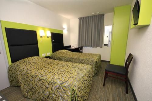 a hotel room with two beds and a chair at The Originals City, Hôtel et Restaurant Aster, Saint-Avold Nord in Creutzwald-la-Croix