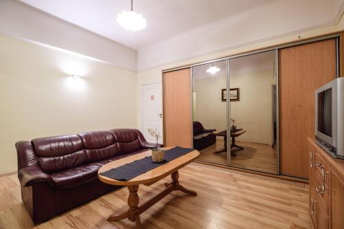 a living room with a leather couch and a table at Golden Lion Guest Rooms Szewska 19 in Kraków