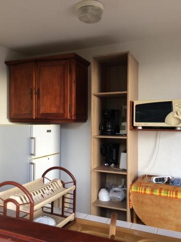 a kitchen with wooden cabinets and a microwave at Gîtes BB in Bouillante