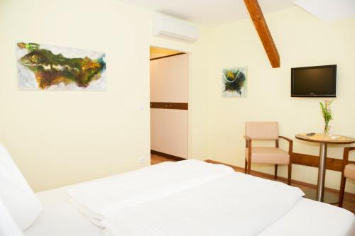 a bedroom with a bed and a table and a tv at Hotel Guidassoni in Leibnitz