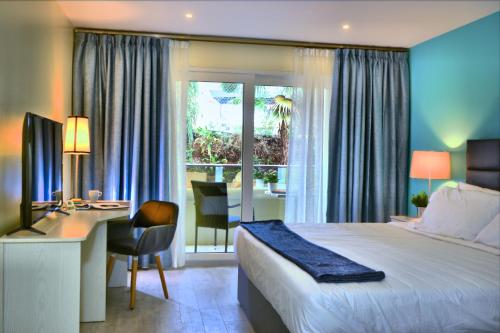 a bedroom with a bed and a desk and a window at Quints Travelers Inn in Willemstad