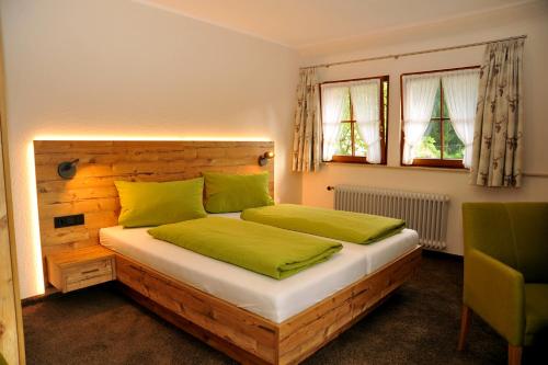 a bedroom with a bed with green sheets and windows at Hotel Gasthaus Zum Hirschen in Simonswald