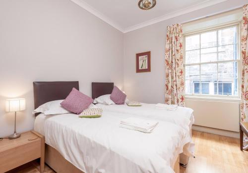 ein Schlafzimmer mit einem großen weißen Bett mit lila Kissen in der Unterkunft Parliament Sq (apt 3) Royal Mile in Edinburgh