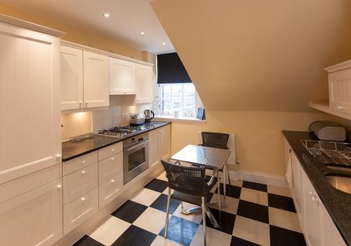 uma cozinha com armários brancos e um piso xadrez em Parliament Sq (apt 5) Royal mile em Edinburgo