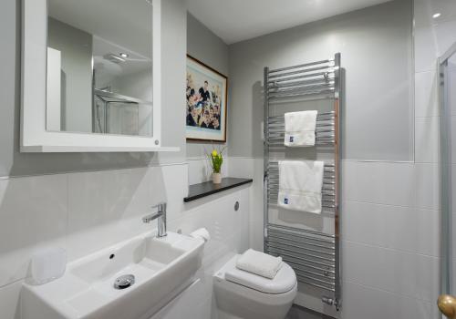 エディンバラにあるParliament Sq (apt 10 ) Royal Mileの白いバスルーム(洗面台、トイレ付)