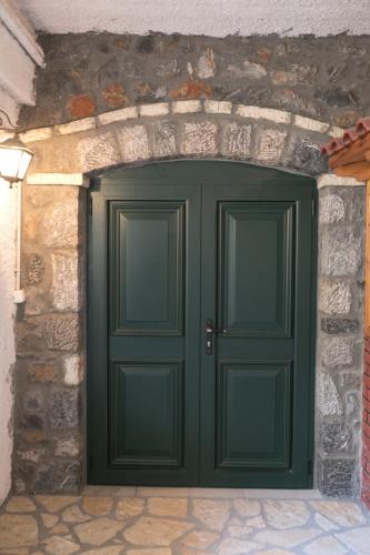 a green garage door in a stone wall at Xenonas Epavli in Levidhion