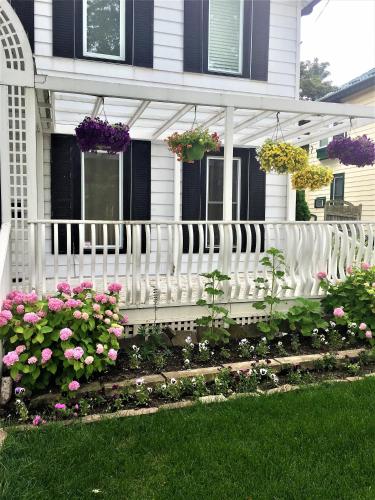 a white fence in front of a house with flowers at Ellis House Bed & Breakfast in Niagara Falls