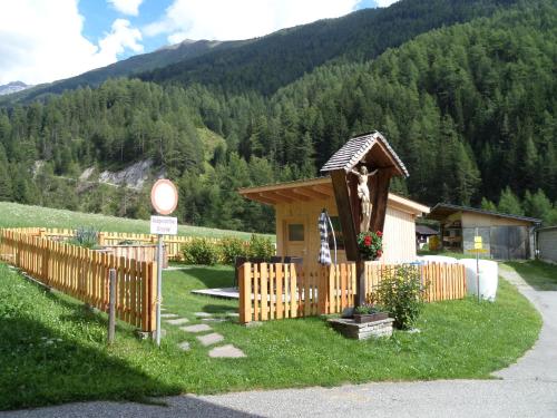 a small house with a wooden fence in the grass at Hoazhof in Kals am Großglockner