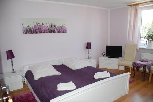 a bedroom with a large bed with a purple blanket at Koral in Koszalin