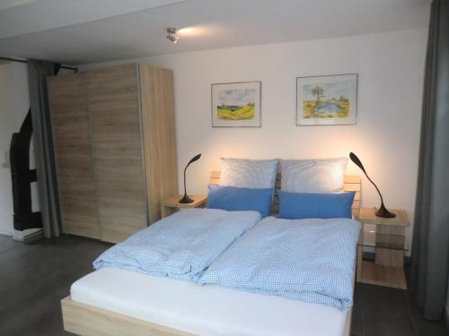 1 dormitorio con 1 cama con sábanas azules y 2 lámparas en Ferienwohnung "im Winkelhof", en Roetgen