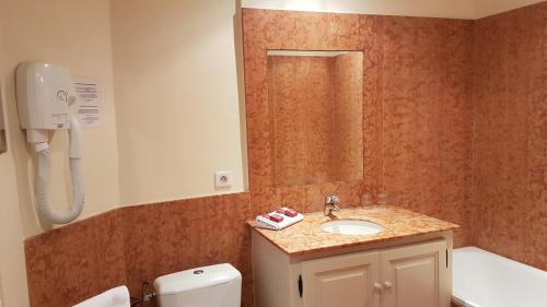 a bathroom with a sink and a toilet and a mirror at Hotel Cardinal in Aix-en-Provence