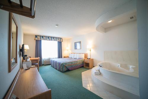 a hotel room with a tub and a bed at River Valley Inn & Suites in Osceola