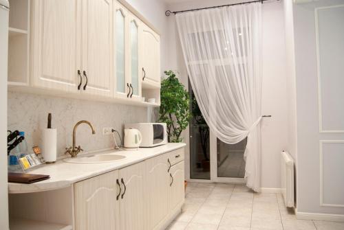 cocina blanca con fregadero y ventana en Sonya Apartments, en Kiev