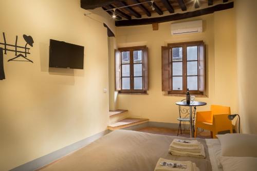 a bedroom with a bed and a tv on the wall at Guesthouse Via Di Gracciano - Adults Only in Montepulciano