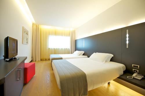 a hotel room with two beds and a television at Mercure Nerocubo Rovereto in Rovereto