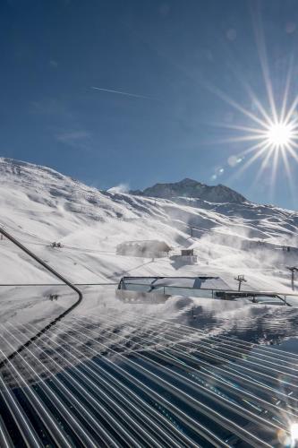 a snow covered mountain with the sun in the sky at SKI - GOLF - WELLNESS Hotel Riml in Hochgurgl