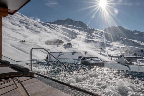 a hot tub on a snow covered mountain with the sun at SKI - GOLF - WELLNESS Hotel Riml in Hochgurgl